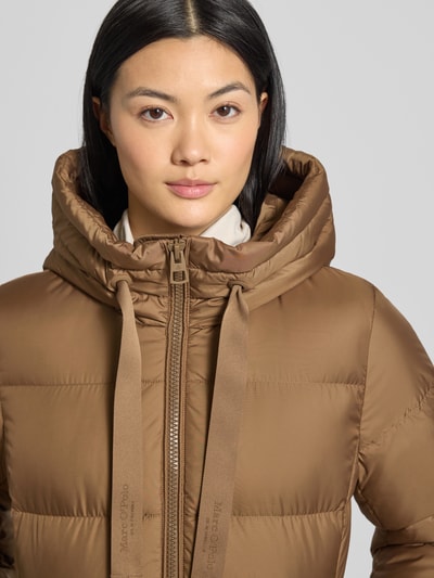 Frauenmodel trägt Shaped Fit Daunenmantel mit Kapuze von Marc O'Polo, Optik: Unifarben, Stehkragen, Zweiwege-Reißverschluss, Label-Applikation, Materialverarbeitung: Stepp, Nahaufnahme Oberkörper.