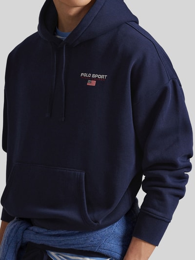 Männermodel trägt Relaxed Fit Hoodie aus Baumwoll-Mix von Polo Ralph Lauren in Dunkelblau mit Label-Schriftzug, Nahaufnahme Oberkörper.