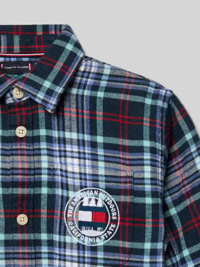Männermodel trägt Regular Fit Freizeithemd aus reiner Baumwolle von Tommy Hilfiger Kids in Mehrfarbig mit Gitterkaro, Logo-Detail, Nahaufnahme Oberkörper.