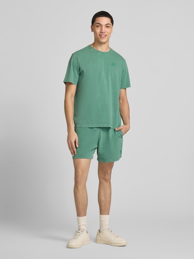 Mężczyznamodel nosi T-Shirt mit Label-Stitching und Rundhalsausschnitt von CHAMPION, męski t-shirt z bawełny, krój regular fit, wyhaftowane logo, okrągły dekolt, długość tyłu w rozmiarze M: 67 cm, cała sylwetka z przodu.