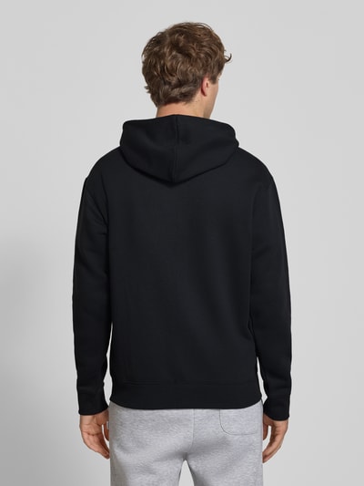 Männermodel trägt Sweatjacke mit Känguru-Tasche und Label-Stitching von New Balance aus schwarzem Baumwoll-Mix, Ganzkörperansicht Rückansicht.