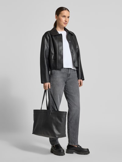 Frauenmodel trägt Shopper mit Label-Detail Modell 'HERA' von LIEBESKIND BERLIN in Schwarz, sichtbare Struktur, Tragehenkel, Ganzkörperansicht von vorne, Maße: Breite 50 cm, Länge 29 cm, Tiefe 17 cm, Schulterriemen 58 cm, Hauptfach mit Magnetverschluss.