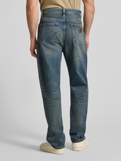 Mannenmodel draagt jeans im Used-Look model 'AARON' van Carhartt Work In Progress van puur katoen, relaxed fit, bandwijdte 44 cm, binnenbeenlengte 77 cm, geheelopname achteraan.