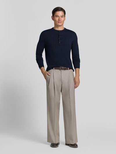 Männermodel trägt Strickpullover mit Henley-Kragen von DRYKORN in Dunkelblau, reine Baumwolle, gerader Schnitt, Ganzkörperansicht von vorne.