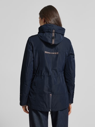 Frauenmodel trägt Funktionsjacke mit Brusttasche von Gil Bret in Dunkelblau mit Kapuze, Stehkragen und Tunnelzug, taillierte Passform, Rückenlänge 74 cm, Schulterbreite 41 cm, Brustweite 47 cm, Ärmellänge 65 cm, Ganzkörperansicht Rückansicht.