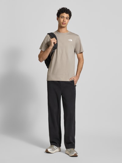 Männermodel trägt Regular Fit T-Shirt aus Baumwoll-Mix Modell 'EVOLUTION' von The North Face in Beige mit Label-Detail, Ganzkörperansicht von vorne. Herren T-Shirt, Rundhalsausschnitt, Rückenlänge bei Größe M: 70 cm.