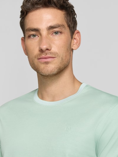 Männermodel trägt T-Shirt mit Rundhalsausschnitt von bugatti in Mintgrün, Baumwoll-Mix, Regular Fit, Label-Detail, Nahaufnahme Oberkörper.