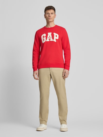 Männermodel trägt Sweatshirt mit Logo und Rundhalsausschnitt von GAP in Rot aus Baumwoll-Mix, Regular-Fit, Ganzkörperansicht von vorne.