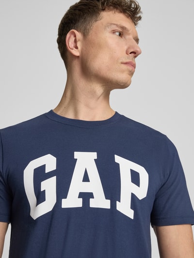 Männermodel trägt T-Shirt mit Logo und Rundhalsausschnitt von GAP aus Reine Baumwolle, Regular-Fit, in Dunkelblau, Nahaufnahme Oberkörper.