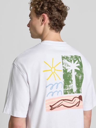 Männermodel trägt Relaxed Fit T-Shirt aus reiner Baumwolle Modell 'NORMAN' von Selected Homme, buntes Grafikmotiv hinten, Ganzkörperansicht Rückansicht, Herren T-Shirt.