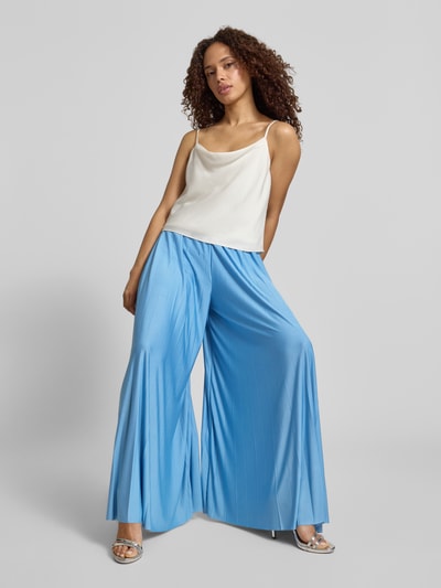 Frauenmodel trägt Stoffhose mit Plisseefalten Modell 'Samantha' von GUIDO MARIA KRETSCHMER WOMAN, hellblau, Satin, Wide Leg Fit, Ganzkörperansicht von vorne.