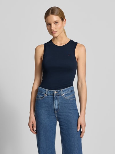 Frauenmodel trägt Slim Fit Tank Top aus reiner Baumwolle Modell 'SLIM CODY' von Tommy Hilfiger in Dunkelblau, unifarben, Logo-Stitching, Ganzkörperansicht von vorne.