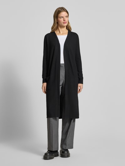 Frauenmodel trägt Longcardigan mit aufgesetzten Taschen Modell 'CITY' von Noisy May, schwarzer Material-Mix mit Stretch-Anteil, Regular-Fit, Rückenlänge 107 cm, Ärmellänge 63 cm, Ganzkörperansicht von vorne.