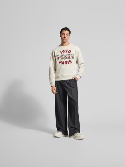 Männermodel trägt Sweatshirt aus reiner Baumwolle von Kenzo mit Label-Print, lockere Passform, Rundhalsausschnitt, elastische Abschlüsse, Rückenlänge 66 cm bei Größe M, cremefarbener Stoff, rote Akzente, weiche Struktur, Ganzkörperansicht von vorne.