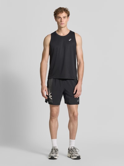 Mężczyzna model nosi Regular Fit Top z nadrukiem z logo Model 'Core' od ASICS TIGER, czarny, okrągły dekolt, długość tyłu 68 cm w rozmiarze M, widok całej sylwetki z przodu
