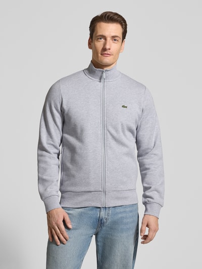 Männermodel trägt Regular Fit Sweatjacke aus Baumwoll-Mix von Lacoste in Optik: Unifarben mit Reißverschluss und Logo-Patch, Ganzkörperansicht von vorne.