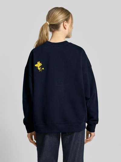 Frauenmodel trägt Loose Fit Sweatshirt aus reiner Baumwolle Modell 'JUMBRELLA EMBO' von Essentiel Antwerp in Dunkelblau, unifarben, Motiv-Print, Pailletten, Perlen, überschnittene Schultern, lange Ärmel, gerippte Abschlüsse, Ganzkörperansicht Rückansicht.