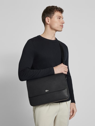 Männermodel trägt Umhängetasche mit Label-Applikation van Lacoste, effen kleuren, ritssluiting, magneetsluiting, hoofdvak, binnenvak, verstelbare schouderband, rechthoekig model, materiaalverwerking: generfd leer, Ganzkörperansicht van voren