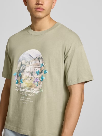 Männermodel trägt T-Shirt mit Rundhalsausschnitt von Jack & Jones in Grün mit Print, Reine Baumwolle, Regular-Fit, Nahaufnahme Oberkörper.