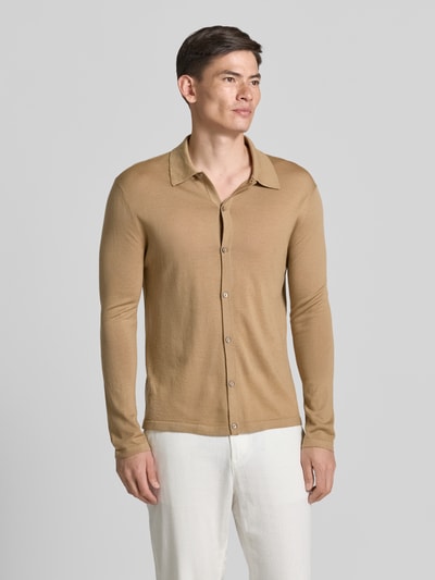 Męski model nosi Regular Fit Strickjacke aus Wolle Modell 'Verklin' od Tiger Of Sweden, kolor beżowy, krój regular fit, kołnierzyk typu kent, listwa guzikowa, długość tyłu w rozmiarze M: 71 cm, długość rękawów w rozmiarze M: 65 cm, struktura gładka, widok całej sylwetki z przodu.