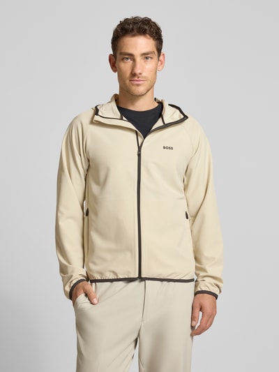 Männermodel trägt Regular Fit Funktionsjacke aus wasserdichtem Material Modell 'L_COMMUTER' von BOSS Green in Beige, Ganzkörperansicht von vorne.