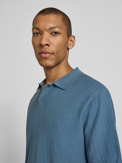 Männermodel trägt Regular Fit Poloshirt aus Baumwoll-Leinen-Mix Modell 'MATTIS' von SELECTED HOMME in Blau, strukturierte Optik, Nahaufnahme Oberkörper.