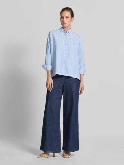 Modelka nosi Relaxed Fit Damenbluse mit Streifenmuster od Emily Van den Bergh, bawełna, niebieskie paski, kołnierzyk, guziki, widok całej sylwetki z przodu