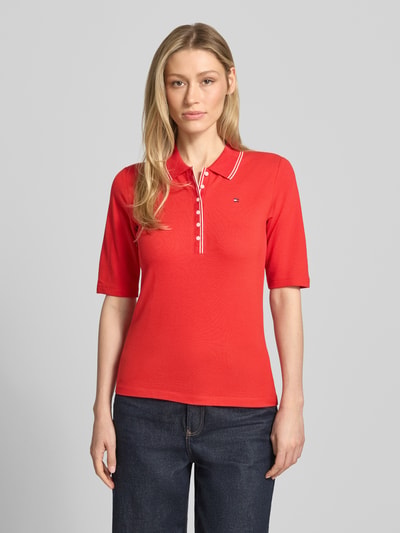 Frauenmodel trägt Slim Fit Poloshirt aus Lyocell-Mix von Tommy Hilfiger, Optik: Unifarben, Logo-Stitching, Kontraststreifen, 1/2-Arm, Materialverarbeitung: Piqué, Ganzkörperansicht von vorne.