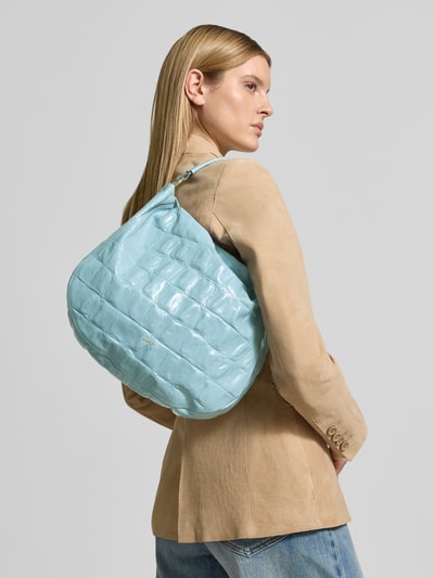 Frauenmodel trägt Handtasche mit Logo-Applikation Modell 'Mia' von Abro in Hellblau mit Strukturmuster, Hauptfach mit Reißverschluss, Schulterriemen, Breite 35 cm, Länge 32 cm, Tiefe 9 cm, Länge Schulterriemen 106 cm, Ganzkörperansicht Rückansicht.
