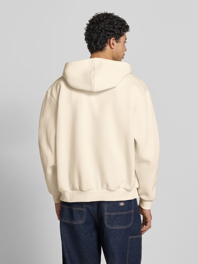 Männermodel trägt Oversized Sweatjacke mit Logo-Stitching von KARL KANI in Beige, Baumwoll-Mix, Kapuze, elastische Abschlüsse, Ganzkörperansicht Rückansicht.
