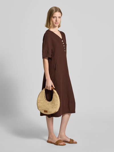 Frauenmodel trägt knielanges Kleid aus Leinen-Viskose-Mix Modell 'Lava' von FREE/QUENT in Braun, A-Linie, V-Ausschnitt, Knopfleiste, strukturierte Oberfläche, Ganzkörperansicht von vorne. Kontext: Damen Kleid, Rückenlänge bei Größe S: 96 cm, Brustweite bei Größe S: 43 cm, Ärmellänge bei Größe S: 29 cm.