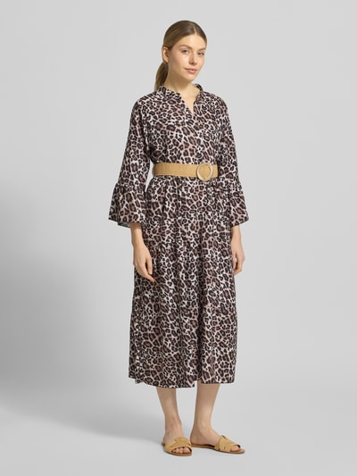 Vrouwenmodel draagt getailleerd dames midi-jurk met serafinohals, korte knoopsluiting, riem, trompetmouwen en volantzoom, model 'Ol44ivi' van ZABAIONE, ruglengte 119 cm, borstwijdte 47 cm, mouwlengte 49 cm, dierenprint in bruin- en beigetinten, geheel lichaamsvooraanzicht.