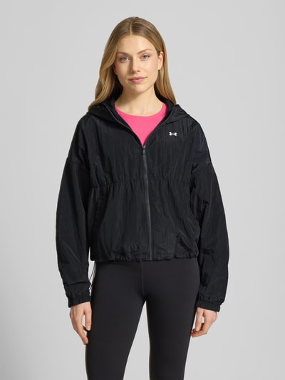 Frauenmodel trägt Jacke mit Kapuze und Logo von Under Armour in Schwarz, Regular-Fit, Reißverschluss, Ganzkörperansicht von vorne, Rückenlänge bei Größe S 57 cm, Schulterbreite 66 cm, Brustweite 64 cm, Ärmellänge 51 cm.