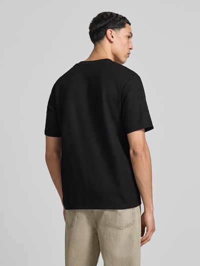 Männermodel trägt T-Shirt mit Stehkragen Modell 'AUSTIN' von Jack & Jones im schwarzen Farbton, Elastischer-Material-Mix, Gerader-Schnitt, Rückenansicht, Ganzkörperansicht Rückansicht.