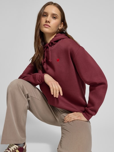 Frauenmodel trägt Regular Fit Hoodie aus Baumwoll-Mix Modell 'CHILLI' von Pieces, Optik: Unifarben, Stickerei, Kapuze mit Tunnelzug, Langarm, Ärmelabschluss: Gerippt, Materialverarbeitung: Sweat, Material: Baumwoll-Mix, sanfte Textur in Bordeaux und Beige, Nahaufnahme Oberkörper.