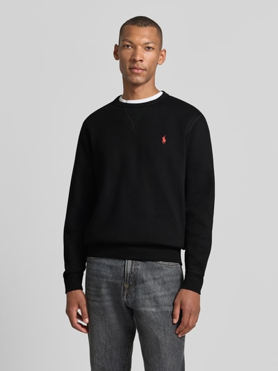 Mannelijk model draagt Regular Fit sweatshirt van katoenmix van Polo Ralph Lauren in zwart met rood logo, vooraanzicht bovenlichaam.
