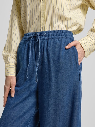 Frauenmodel trägt Loose Fit Hose aus Bio-Baumwoll-Lyocell-Mix Modell 'KELAANI' von Armedangels in Denimoptik, elastischer Bund mit Tunnelzug, seitliche Eingrifftaschen, Nahaufnahme Oberkörper.