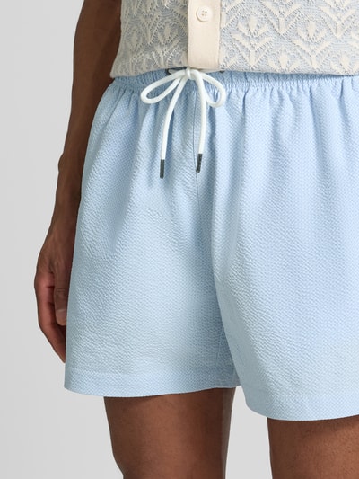 Männermodel trägt Badehose mit elastischem Bund und Gesäßtasche von MCNEAL in Hellblau, strukturierte Oberfläche, Regular Fit, Tunnelzug, Nahaufnahme Oberkörper.