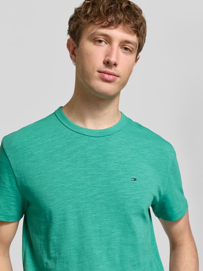 Männermodel trägt Regular Fit T-Shirt aus reiner Baumwolle von Tommy Jeans, Optik: Unifarben, Logo-Detail, Jersey, Nahaufnahme Oberkörper.