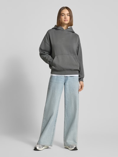 Vrouwenmodel draagt oversized hoodie met logo en kangoeroezak, model 'CLARITA' van Pegador, katoenmix, dames, grijs, voorkant volledig.