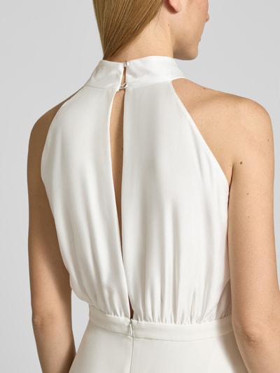 Vrouwenmodel draagt Jumpsuit met Schleifen-Applikation van SWING in wit met halter, cut-out op de rug, detailopname rug. Context: Dames Jumpsuit van SWING, getailleerd model, wijde benen, halter, strikapplicatie, cut-out op de rug, ruglengte maat 36: 150 cm, borstwijdte maat 36: 36 cm, totale lengte maat 36: 155 cm, binnenbeenlengte maat 36: 80 cm.