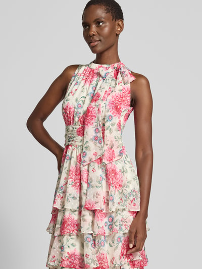Frauenmodel trägt Maxikleid mit Schluppe Modell 'Marli' von Neo Noir aus Chiffon, taillierter Schnitt, Rundhalsausschnitt, Volantsaum, florales Muster; Kontext: Damen Maxikleid von Neo Noir, rückseitiger Schlüsselloch-Ausschnitt mit Knöpfen, Smok-Details, Rückenlänge 145 cm, Brustweite 42 cm; Nahaufnahme Oberkörper.