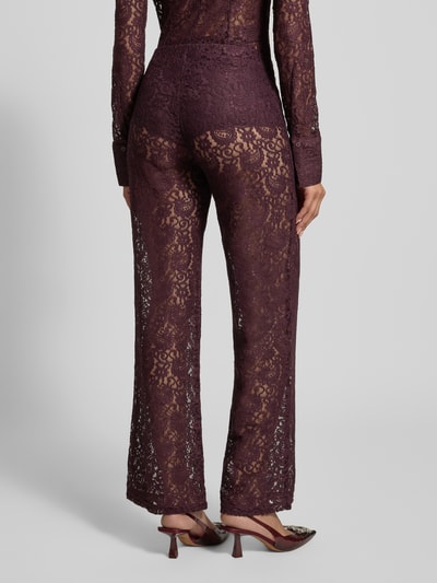 Frauenmodel trägt Stoffhose aus Spitze Modell 'GRACE' von Mango in dunklem Lila, transparenter Spitzenstoff mit Paisley-Muster, Blickdichter Unter-Pantie, Relaxed Fit, elastisches Material, Ganzkörperansicht Rückansicht.
