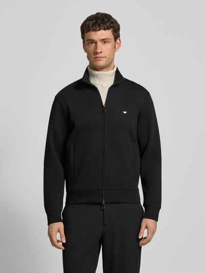 Männermodel trägt schwarze Regular Fit Sweatjacke mit Logo-Stitching von Emporio Armani aus elastischem Baumwoll-Mix, Stehkragen, Zweiwege-Reißverschluss, Eingrifftaschen und elastischen Abschlüssen, Rückenlänge 65 cm, Ärmellänge 64 cm, Ganzkörperansicht von vorne.