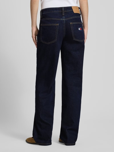 Frauenmodel trägt Straight Fit Jeans aus Baumwoll-Mix Modell 'SOPHIE' von Tommy Jeans in dunkler Denim-Optik mit Label-Patch, Label-Prägung, 5-Pocket-Design, Gürtelschlaufen, Dark Wash, Materialverarbeitung Twill, Low Waist Bund, Detailaufnahme Ganzkörperansicht Rückansicht.