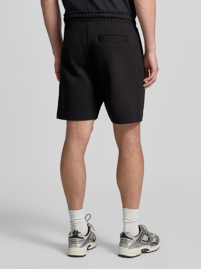 Männermodel trägt schwarze Regular Fit Sweatshorts aus Baumwoll-Mix Modell 'JT_SHORTS' von BOSS Green, Ganzkörperansicht Rückansicht.
