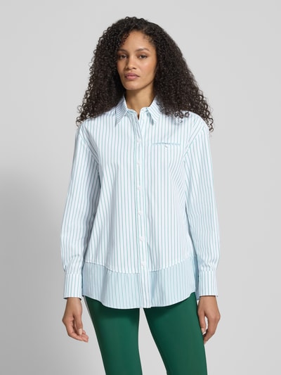 Frauenmodel trägt Regular Fit Bluse mit Brusttasche von Marc Cain in Weiß mit blauen Streifen, reine Baumwolle, Hemdblusenkragen, Knopfleiste, Ganzkörperansicht von vorne.