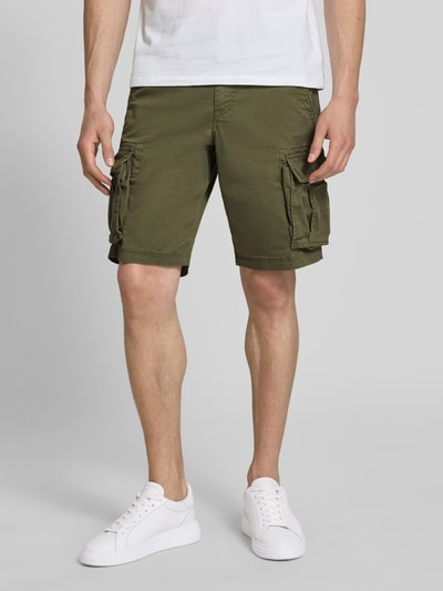 Männermodel trägt Straight Fit Shorts mit Cargo-Taschen Modell 'Core' von GAP in Olivgrün aus elastischem Baumwoll-Mix, Nahaufnahme Oberschenkel. Baumwollstruktur und Eingriff- sowie Gesäßtaschen, Knopf- und Reißverschluss sichtbar.