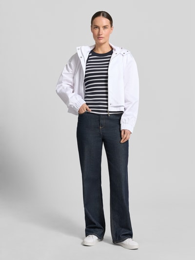 Frauenmodel trägt Jacke mit Stehkragen und verdecktem Reißverschluss von monari in Weiß mit Reißverschlusstaschen, Regular-Fit, Ganzkörperansicht von vorne. Rückenlänge 49 cm, Schulterbreite 55 cm, Brustweite 57 cm, Ärmellänge 58 cm bei Größe 36.