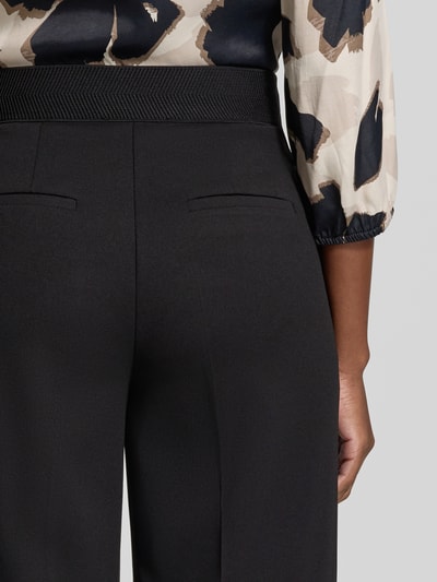 Frauenmodel trägt Regular Fit Weite Hose mit Bügelfalten Modell 'LT JULI' von Betty Barclay, schwarze Farbe, Detailaufnahme Rückansicht, Damen Weite Hose von Betty Barclay.